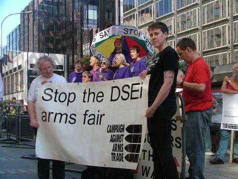 CAAT protesters hold a large white banner which says 'Stop the DSEi arms fair'