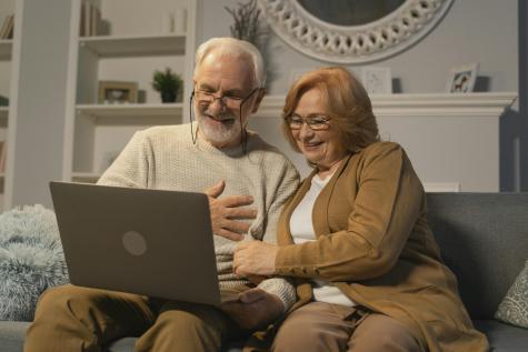 Elderly Couple Sitting on a Couch while in a Video Call Using a Laptop.