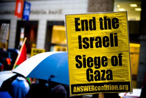 At a pro-Palestine demonstration there is a large yellow poster which says 'End the Israeli Siege of Gaza'.