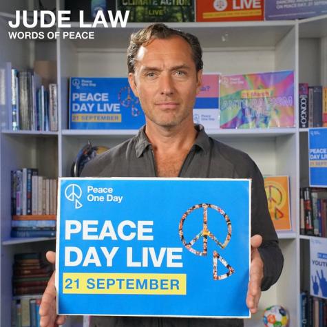 Jude Law, Peace One Day ambassador holds up a sign with the details of the 2025 Peace One Day Campaign.