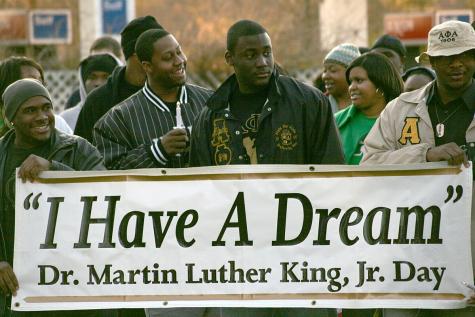 Black men and women gather to celebrate Martin Luther King, Jr. Day, they hold a large banner which says 'I have a dream.'