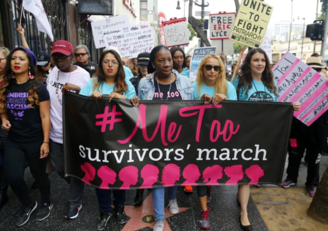Many people line the streets at a women's rights demonstration. At the front there are five women holding a large black sign that says '#MeToo Survivors' March'