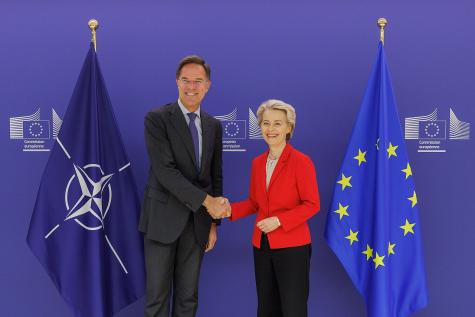 NATO Secretary General Mark Rutte with President of the European Commission Ursula von der Leyen in Brussels, 29 October 2024. They stand shaking hands looking into the camera infont of the NATO and EU flags.