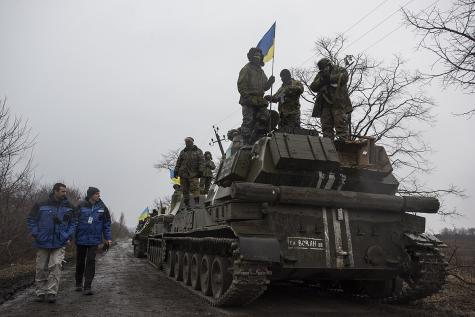 OSCE SMM monitoring the movement of heavy weaponry in eastern Ukraine. Ukraine tanks move along a road while OSCE agents walk alongside them.
