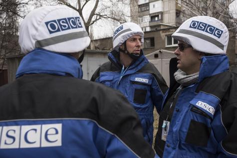 OSCE SMM monitoring the movement of heavy weaponry in eastern Ukraine. Three men wear the uniform and helmets of the OSCE.
