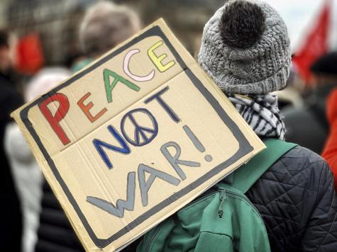 Stop the War rally at London's Trafalgar Square on Saturday 11 January 2020. PIcture taken of a prtoester from behind holding a cardboard sign that says 'Peace Not War'.
