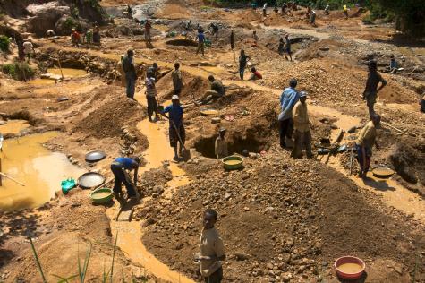 Child miners as young as 11 at work in Eastern Congo. They are working with shovels and buckets and are surrounded by puddles of water and mud.