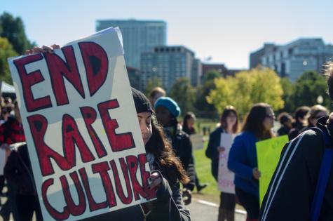 At a march against rape culture and gender inequality a woman holds up a large sign that says 'End rape culture'.