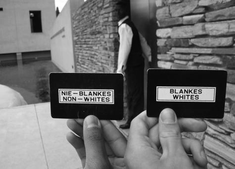 A example of racial segregation in apartheid South Africa. A person holds up two cards one which says non-Whites and one which says Whites