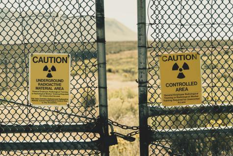 Two gated fenced are chained together each with a yellow radiation warning sign.