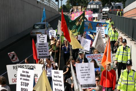 Protesters march down a road in the UK to demonstrate against the DSEi arms fair.