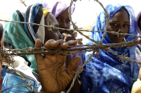 Three Sudanese refugee women stand at a barbed wire fence in Zam Zam camp outside El Fasher, Sudan.