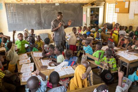 Image of a male teacher delivering a class to an overcrowded classroom in Burkina Faso.