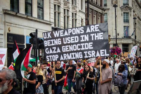 Protesters gather in Trafalgar Square, London to demonstrate against the war in Gaza. They hold a large black sign that says 'UK weapons are being used in the Gaza genocide. Stop arming Israel."