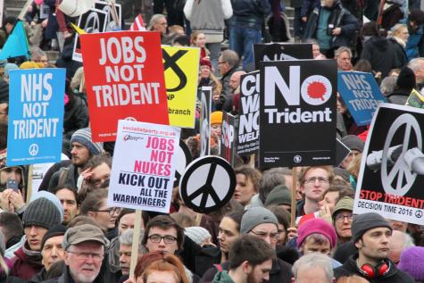 Stop Trident Demonstration. Protesters line the street holding signs which say 'Jobs not Trident' and 'NHS not Trident'