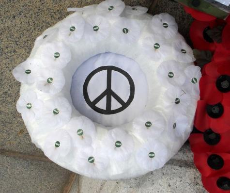 White peace poppies made into a wreath sit on the floor next to a red wreath for Remembrance Day in the UK.