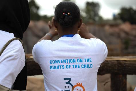 A girl from Ethiopia has her back to the camera, she is wearing a tshirt that says Convention on the Rights of the Child.