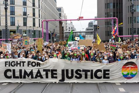 Demonstrators line the street to protest for climate justice. They hold a large white banner that says 'Fight for climate justice'.