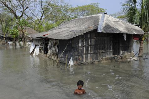 A 10 year old girl takes a bath in the flooded contaminated water that surrounds her home.