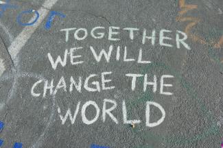 White chalk writing on the floor that says ' Together we will change the world'