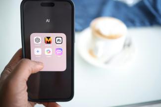 A person holds a phone in their hand with the AI screen open showing all of the available AI apps to download.