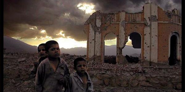 Three desperate children walk through rubble infront of a destroyed building in Afghanistan