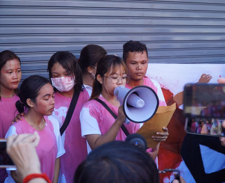 Image of Mother Nature a group of Cambodian activists from Cambodia. Four young activists are covered in food colouring representing blood. One of them holds a megaphone.