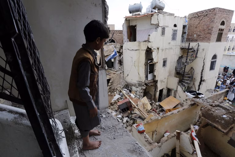 A small child stands on the edge of his destroyed home overlooking his neighborhood in Sana, a day after it was hit  by a Saudi-led airstrike
