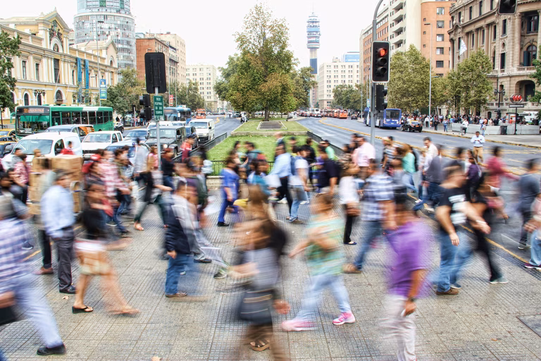  Timelapse photo of people crossing the street. There are many cars and buildings in the background.
