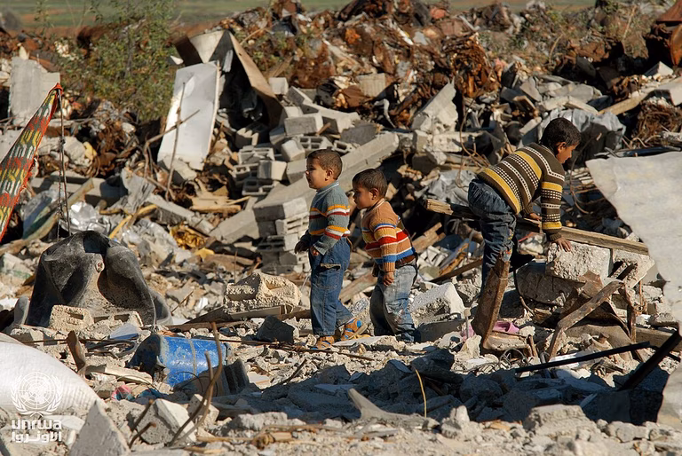 Three young boys are salvaging a destroyed building in the Gaza Strip surrounded by rubble.