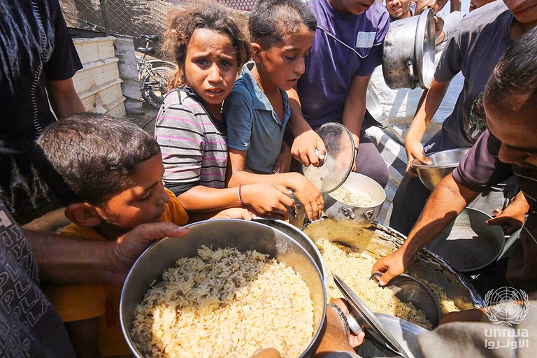 Displaced Palestinians in Deir el-Balah line up to receive food provided by charitable organizations