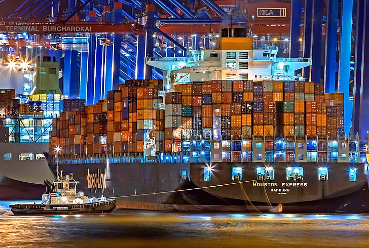 A huge container ship is docked at the port of Hamburg at night.