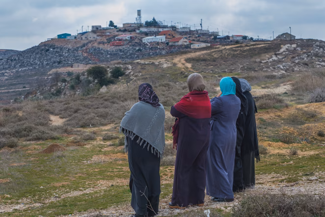 A group of Palestinian women look up at an illegal Israeli outpost in the West Bank village of Jalud. The village has been a frequent target of violence from the settlers surrounding the village.